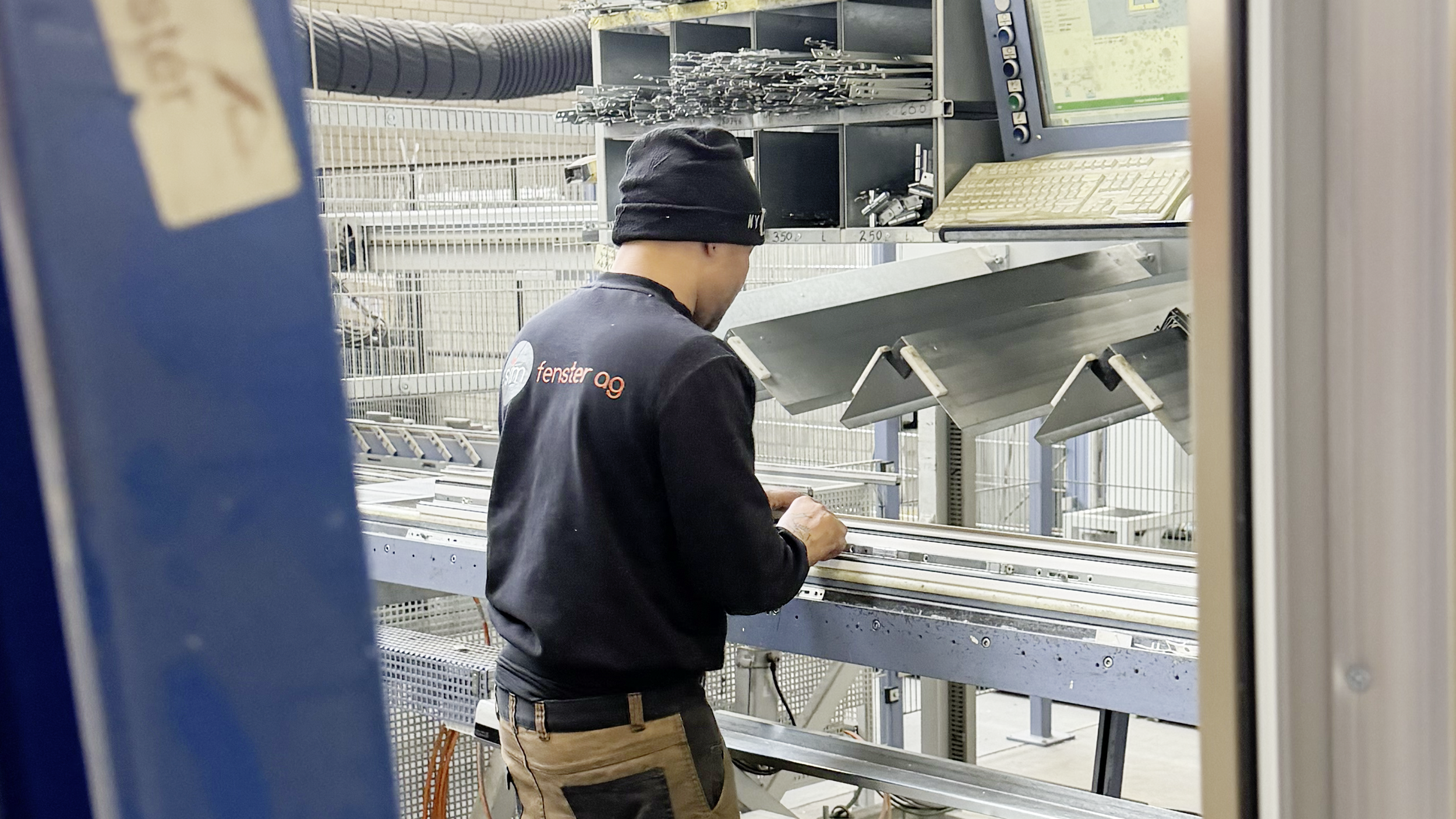 Ein Mann in der Fabrik bei dem Beschlagen von Fensterprofilen