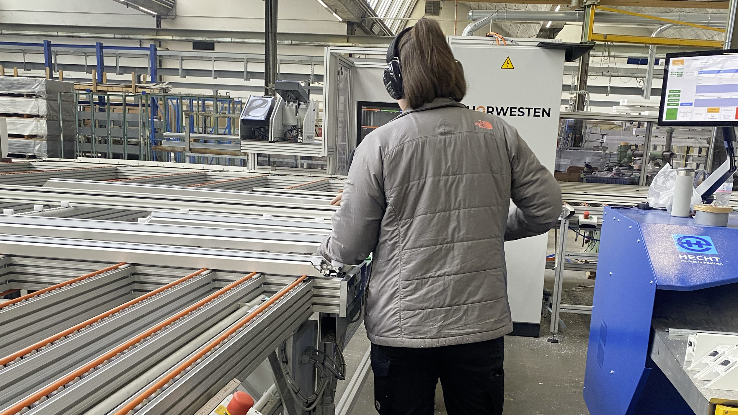 Frau von hinten an der Zuschnittmaschine bei der Fensterproduktion