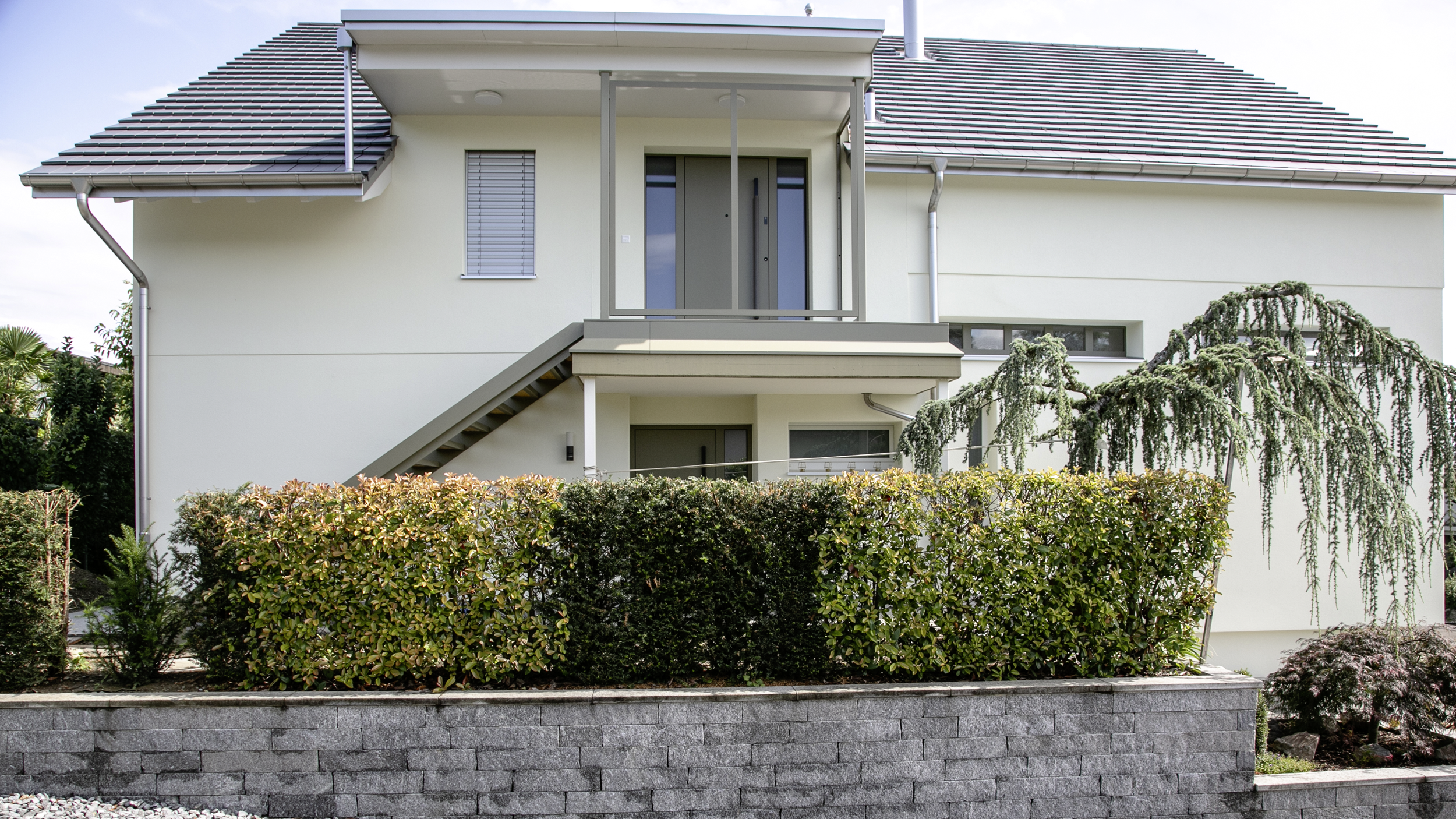 Aussenansicht eines Mehrfamilienhauses mit Eingang und Garten