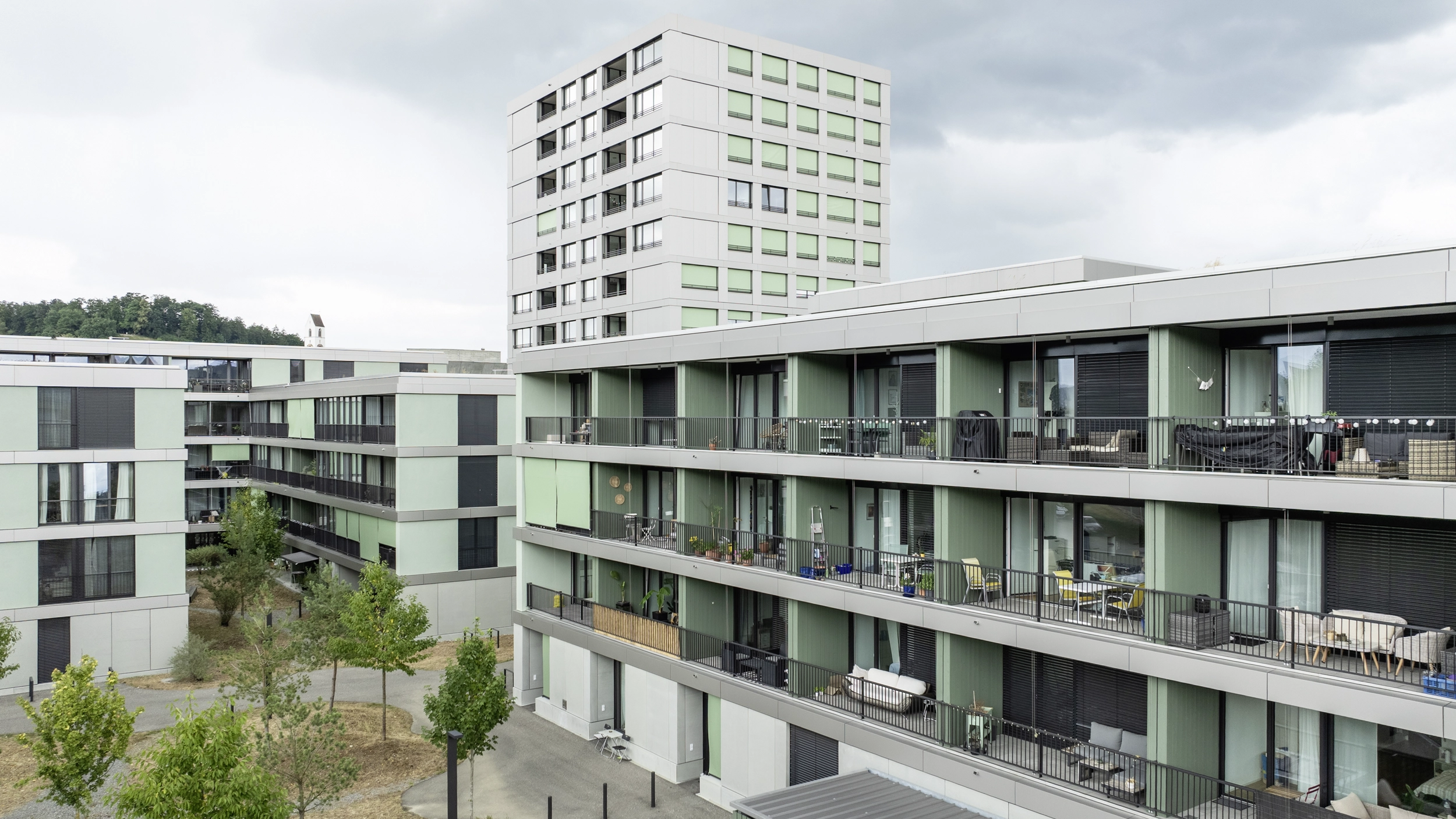 Eine Frau sitzt vor einem grossen Fenster mit Blick auf Wälder und arbeitet 